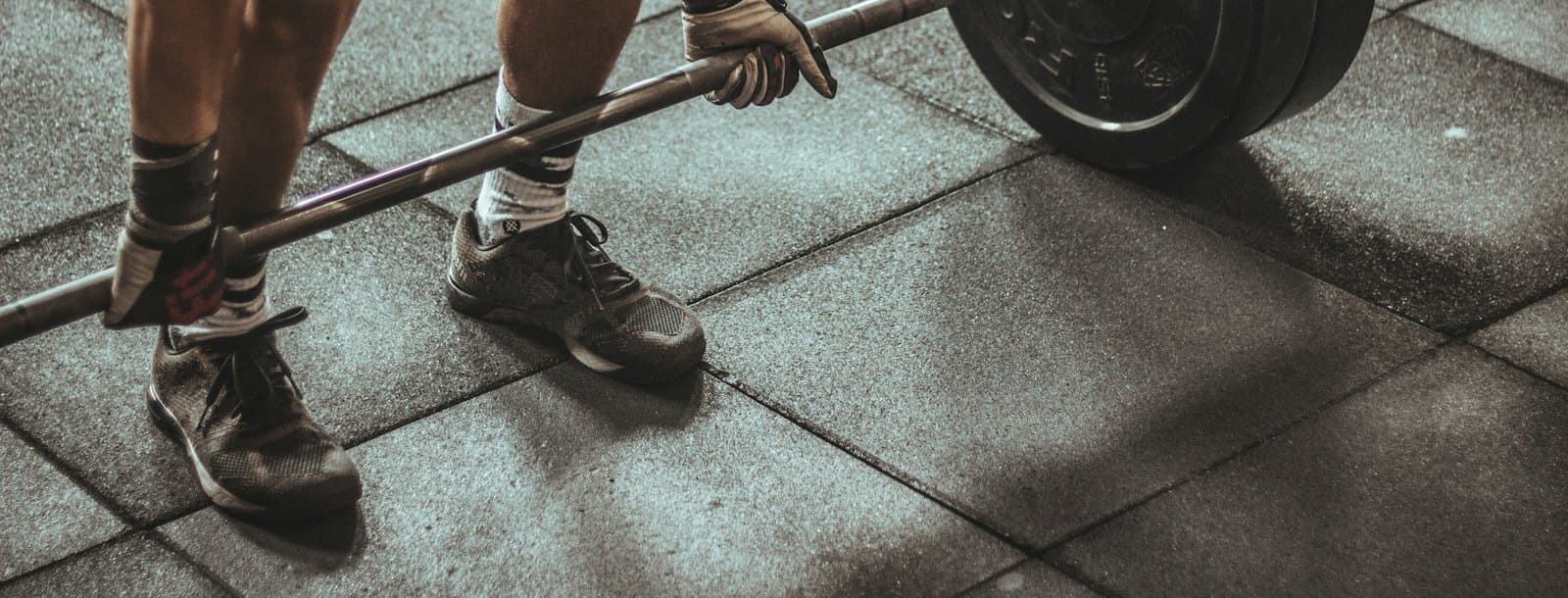 A loaded barbell being pulled from a rubber gym floor