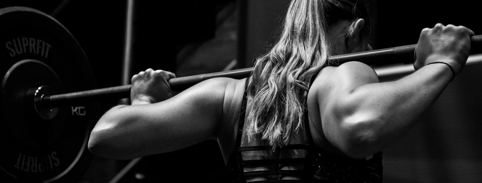 A woman squatting a loaded barbell in a gym