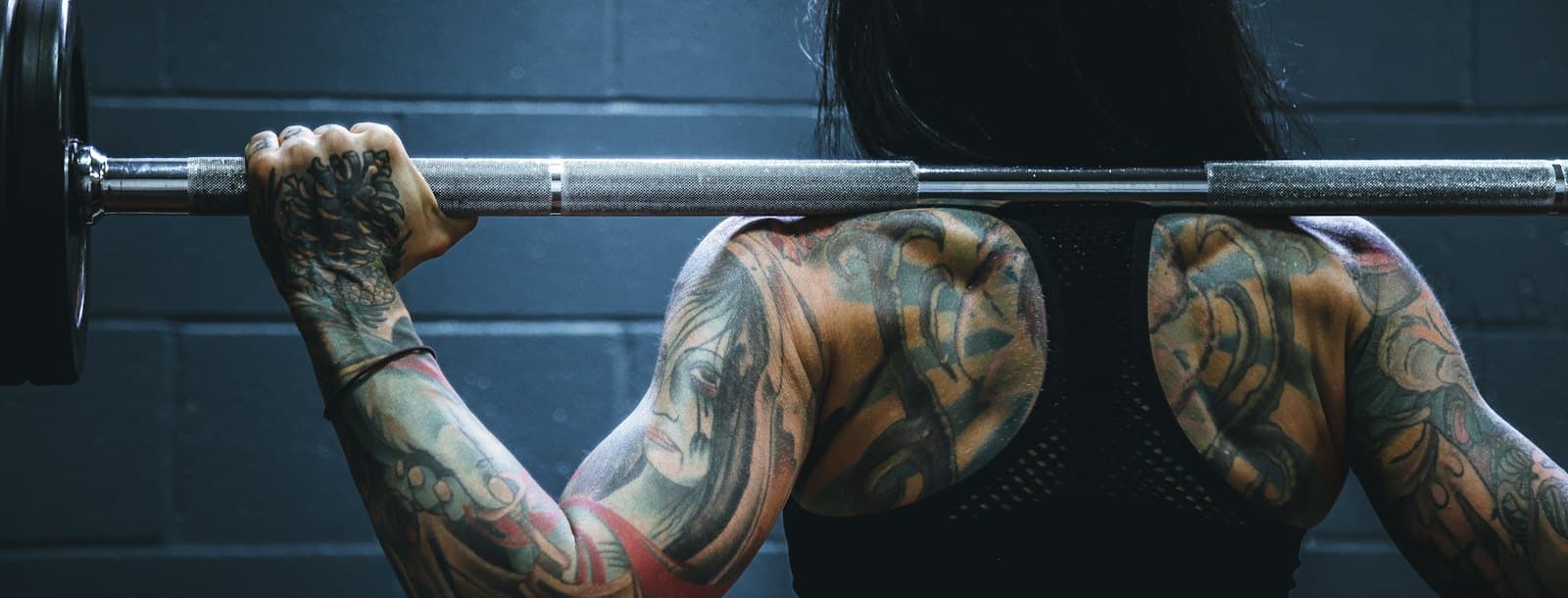 A woman carrying a barbell across a training floor